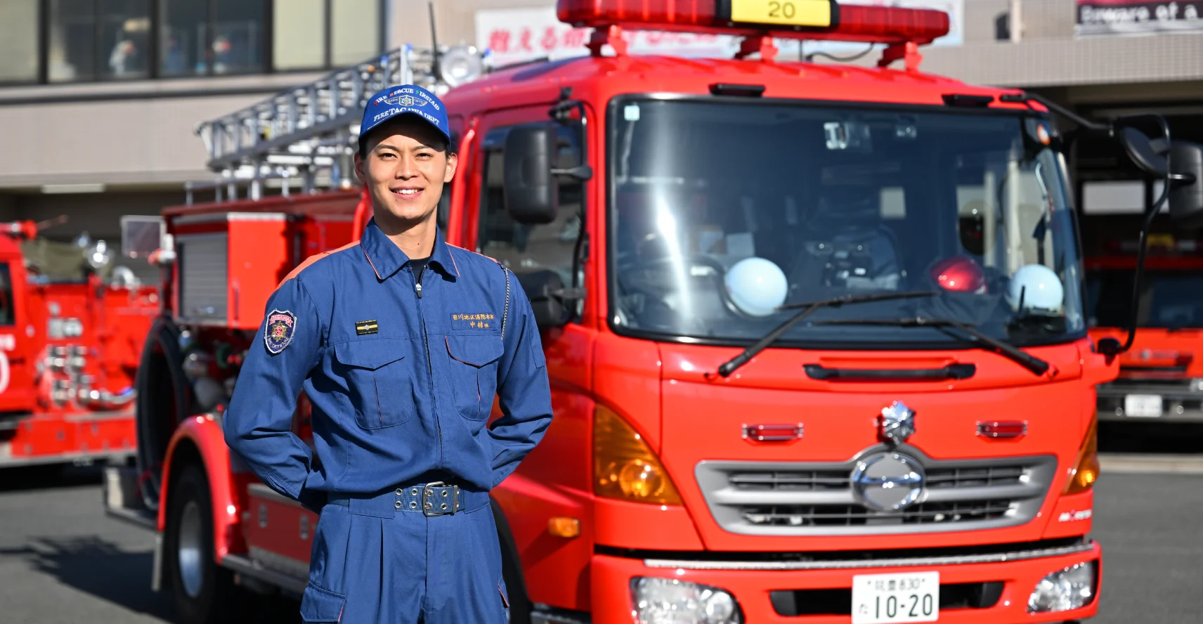 消防車の前で両手を後ろにして立つ中村さんの写真