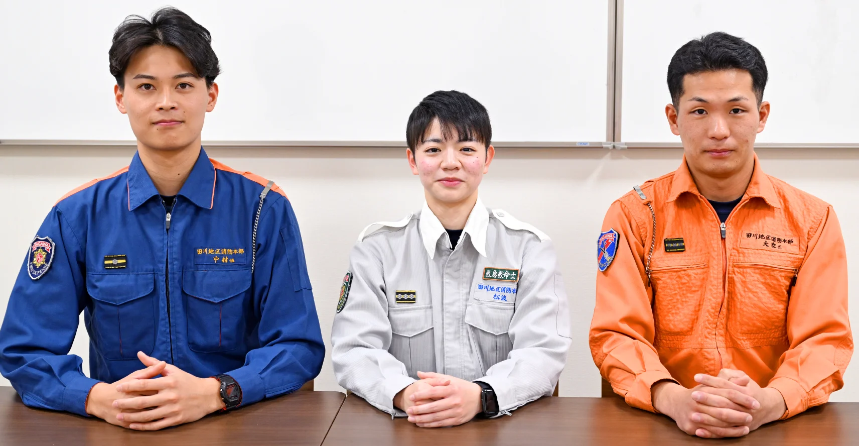 長机の椅子に座った中村さん、松浪さん、大家さんが机の上で手を組んでいる様子