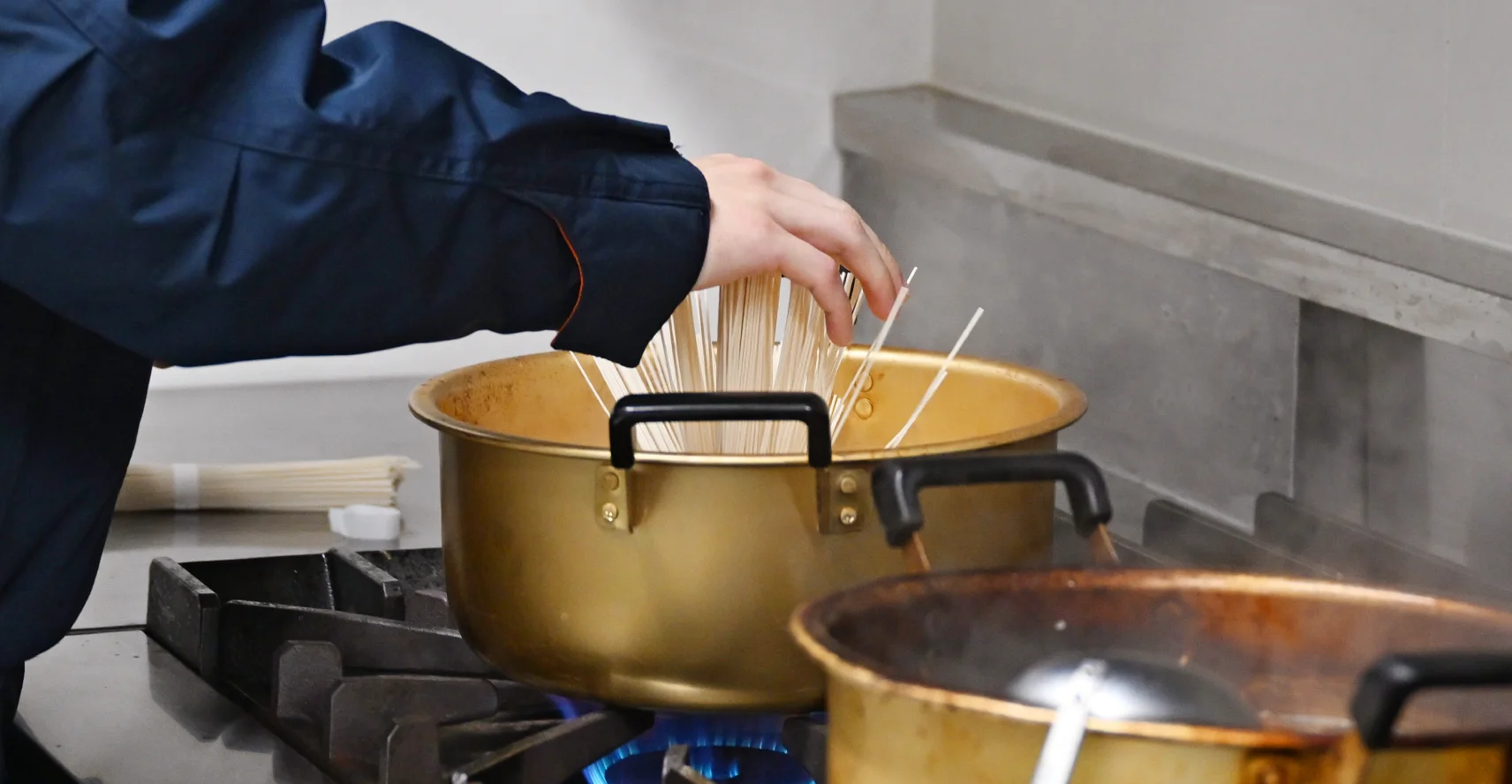 消防隊の人が鍋の中に麺を入れている様子